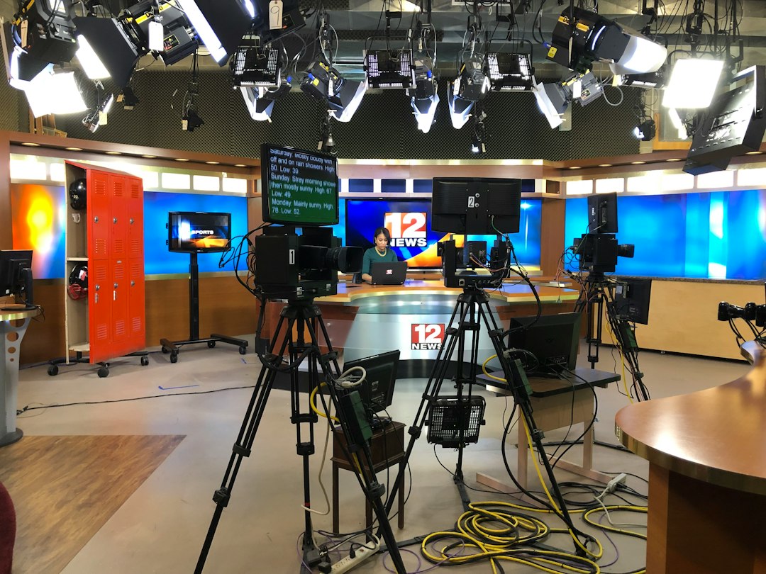 Sala de agência com telas de TV e computador, anotações e espaço para texto
