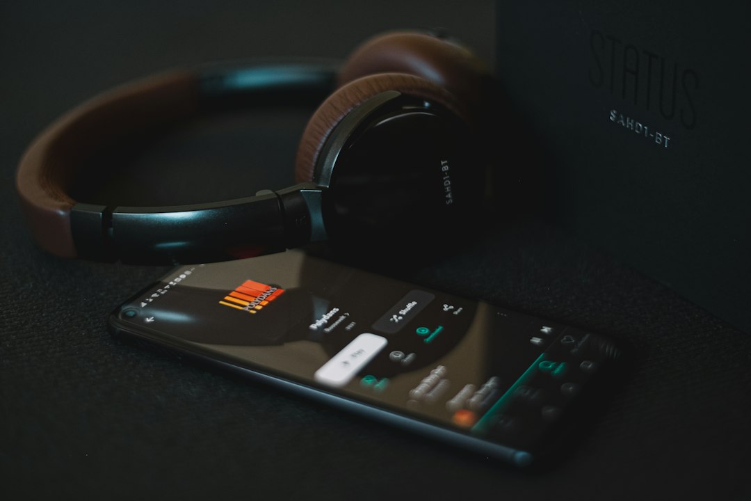 controle remoto preto e branco ao lado de fones de ouvido pretos